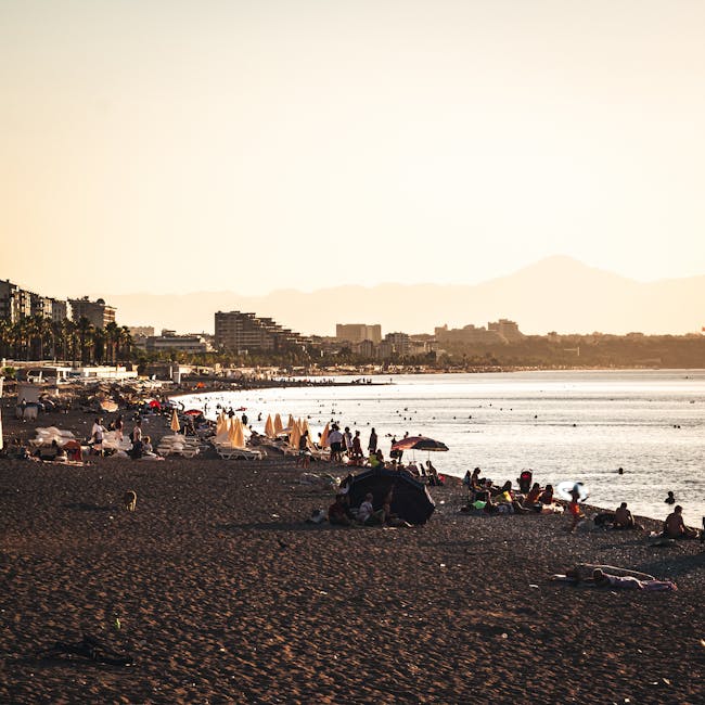 Strand bei Sonnenuntergang mit Badegästen und Skyline von Rhodos