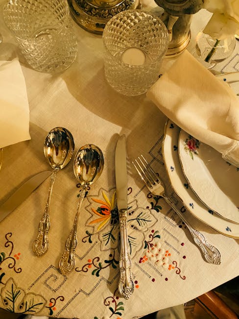 Elegantes Silberbesteck und Kristallgläser auf bestickter Leinentischdecke