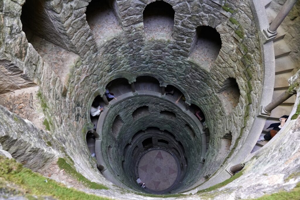 Pozzo a scala elicoidale in pietra visto dall'alto, pareti con nicchie