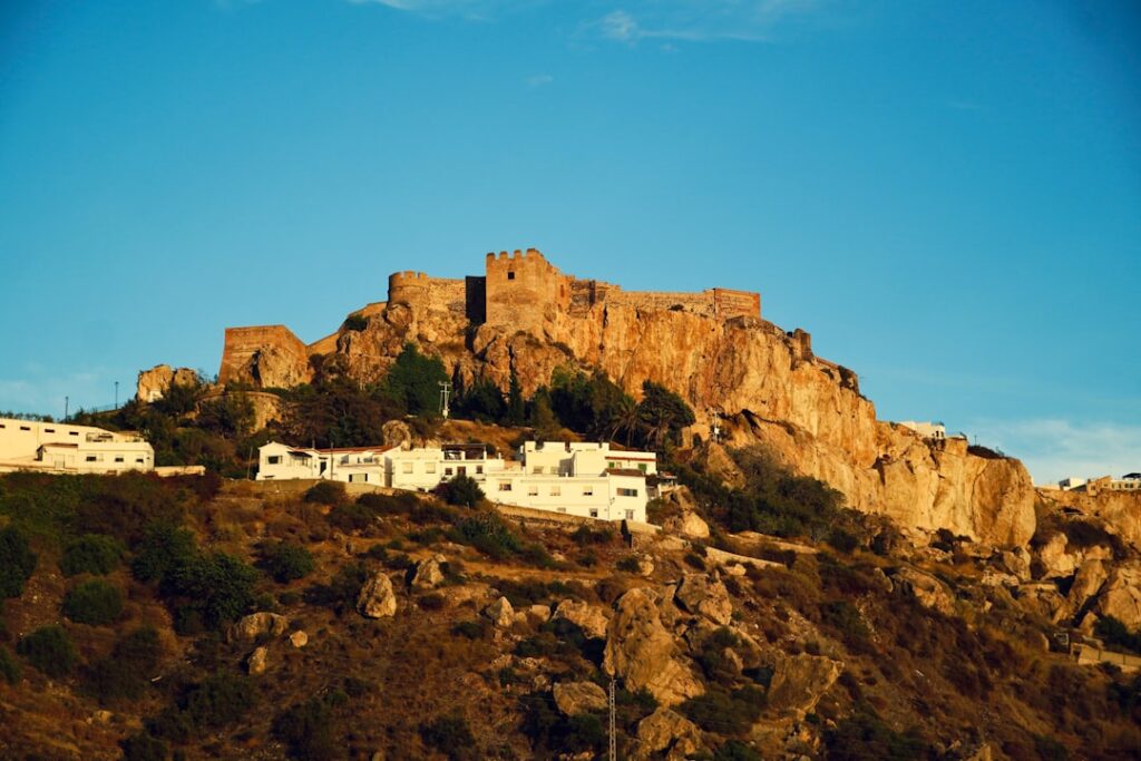 Fortezza su altura rocciosa che domina villaggio con case bianche