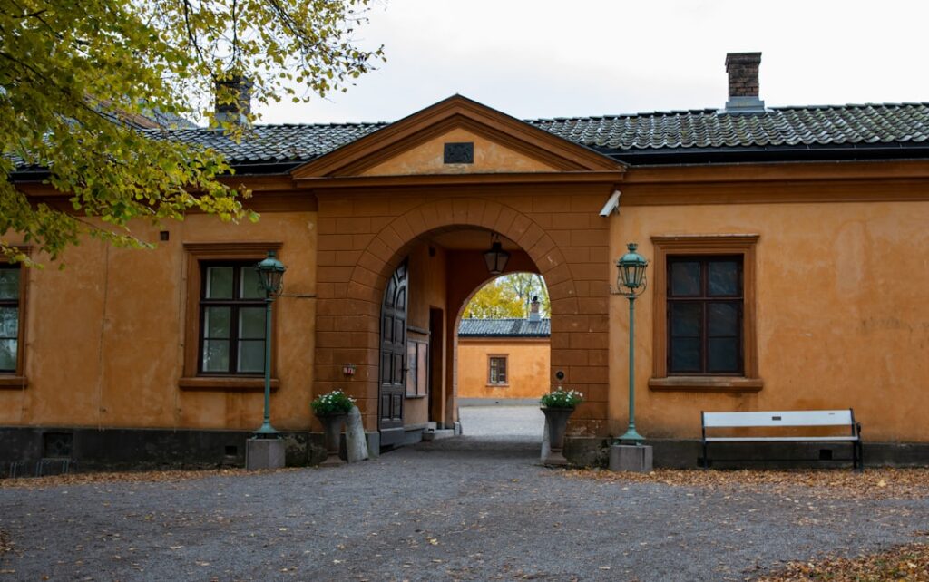 Cortile con arco d'ingresso e panchina davanti a edificio giallo