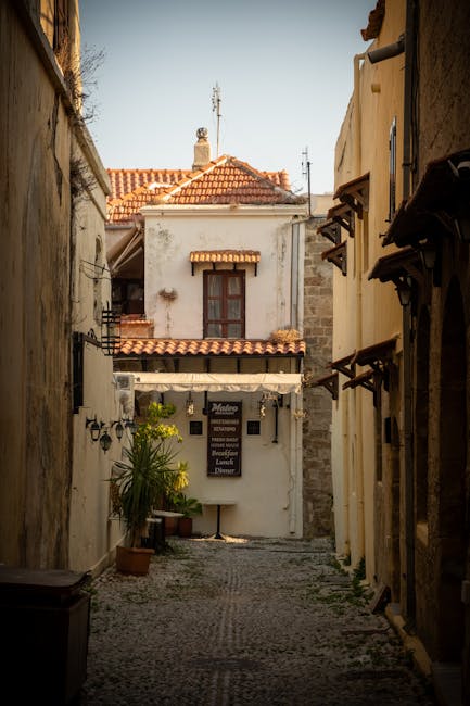 Smal steegje met restaurantbord en terracotta daken in de oude binnenstad van Rhodos