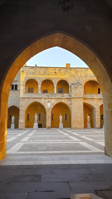 Arched doorway framing the Palace courtyard with statues in Rhodes