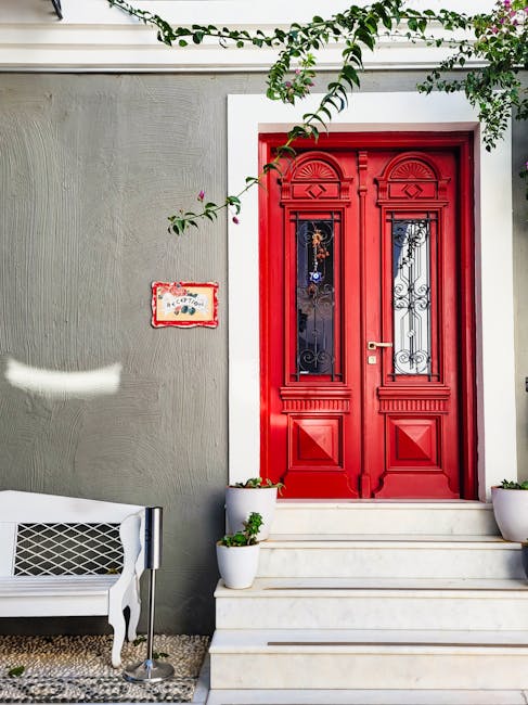 Red double door entrance with white steps and potted plants in Rhodes
