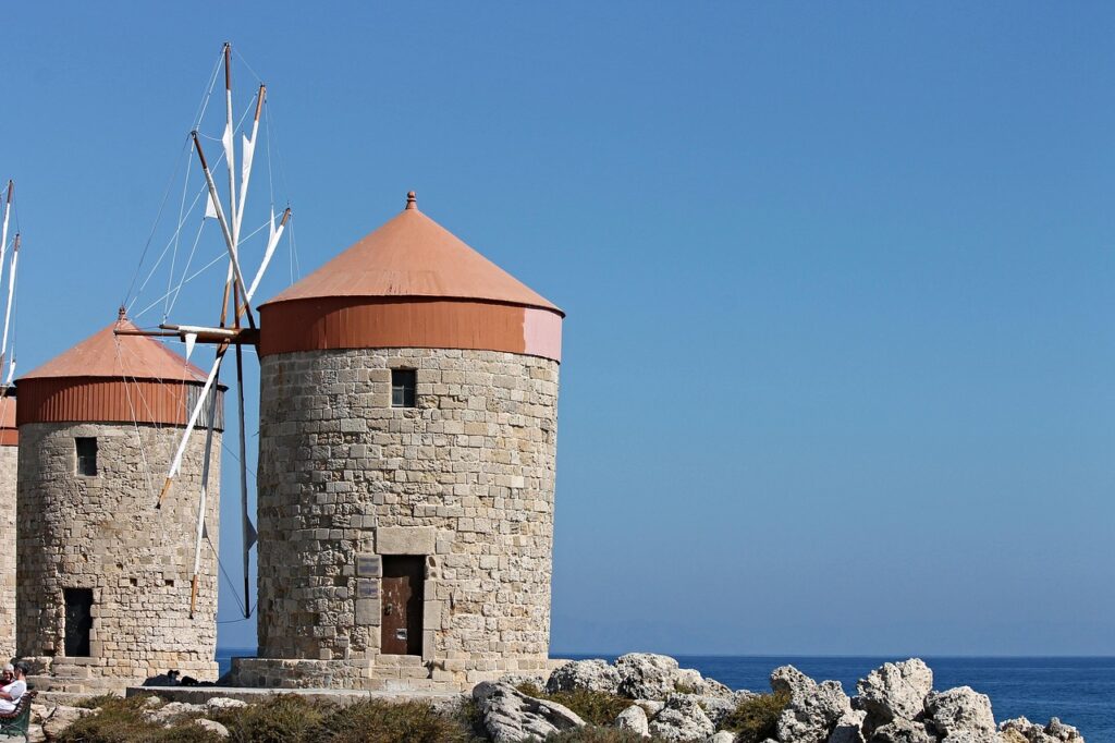 Historische Windmühlen mit roten Dächern an der Küste von Rhodos, blaues Meer