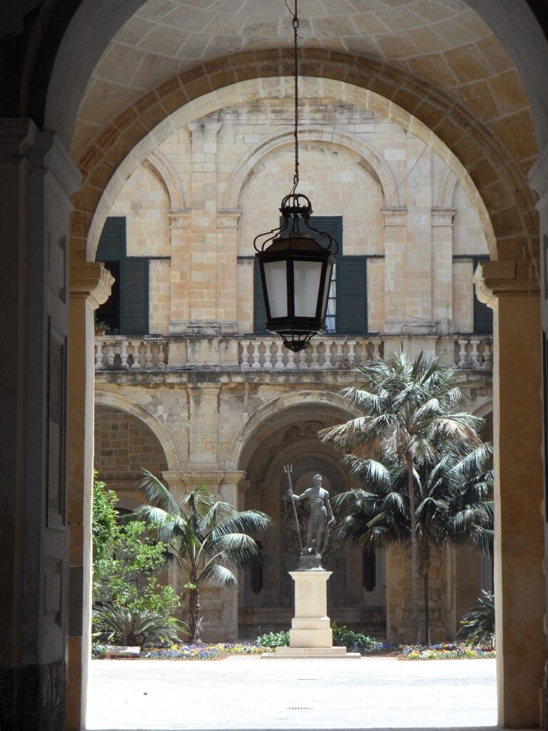 Arcade encadrant la cour du palais de Rhodes avec statue et palmiers