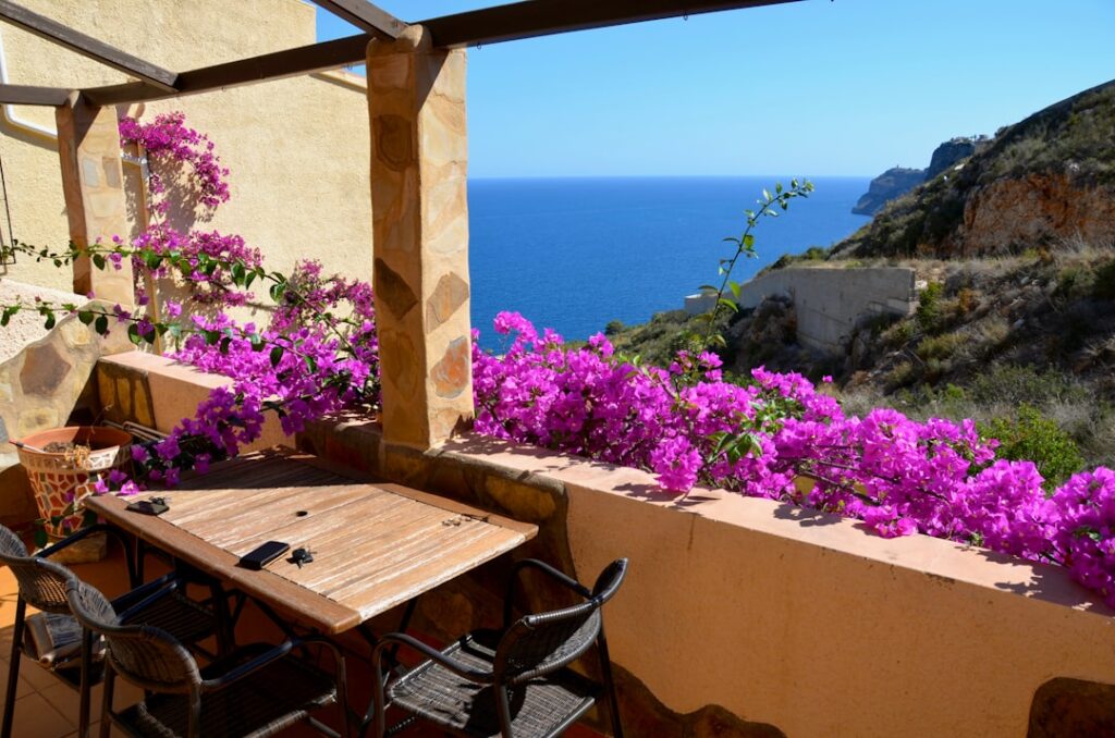 Terrasse mit Holztisch und Bougainvillea, Blick auf die Ägäis bei Rhodos