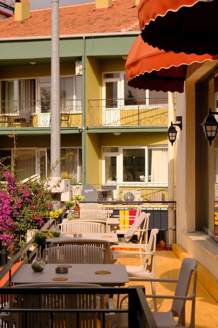 Balkon z stolikami i czerwonymi markizami w hotelu na Rodos