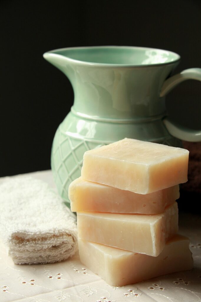 Quatre barres de savon artisanal empilées près d'une cruche verte