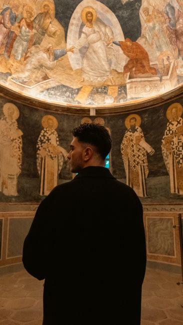 Visiteur contemplant des fresques byzantines dans une chapelle musée à Rhodes