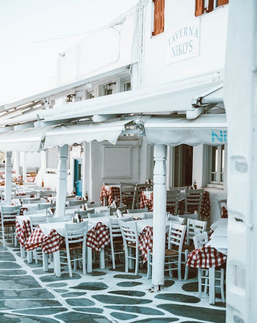 Terrasse d'une taverne mykonienne aux nappes à carreaux rouges, chaises blanches