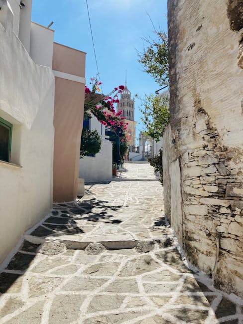 Ruelle en pente pavée, bougainvillier et clocher visible à Mykonos