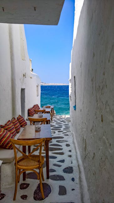Ruelle blanche étroite avec tables menant à la mer à Mykonos