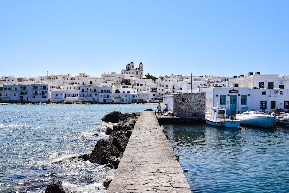 Jetée en pierre menant au port bordé de maisons blanches de Mykonos
