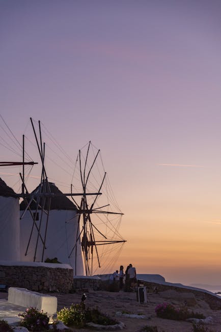 Classic Mykonos windmills silhouetted against purple and orange sunset sky