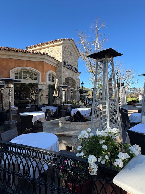 Outdoor Mediterranean restaurant terrace with heaters, white tablecloths and flowers