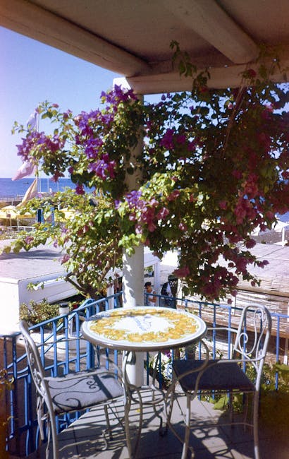 terrasse fleurie avec table en mosaïque et mer en fond, Mykonos