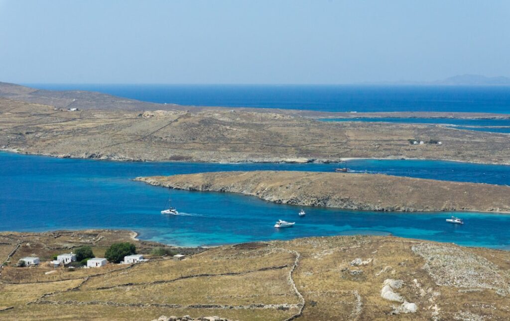 Zeil- en motorboten varen in helder turkoois water bij Mykonos