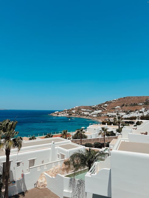 Witte huizen met terrassen en zeezicht boven een baai op Mykonos