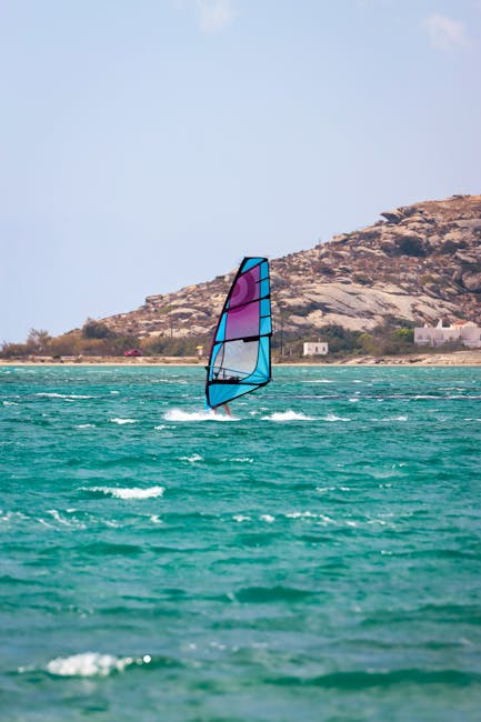 Windsurfer met blauw-paarse zeil op turquoise water bij Mykonos