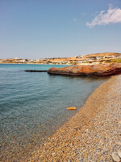 Kiezelstrand met kristalhelder water en rotsachtige kustlijn op Mykonos