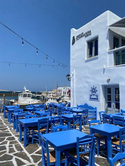 Terrasse de restaurant aux tables bleues face au port de Mykonos