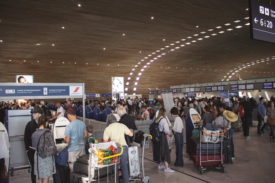 Drukke vertrekhal met lange rijen passagiers en bagagekarren