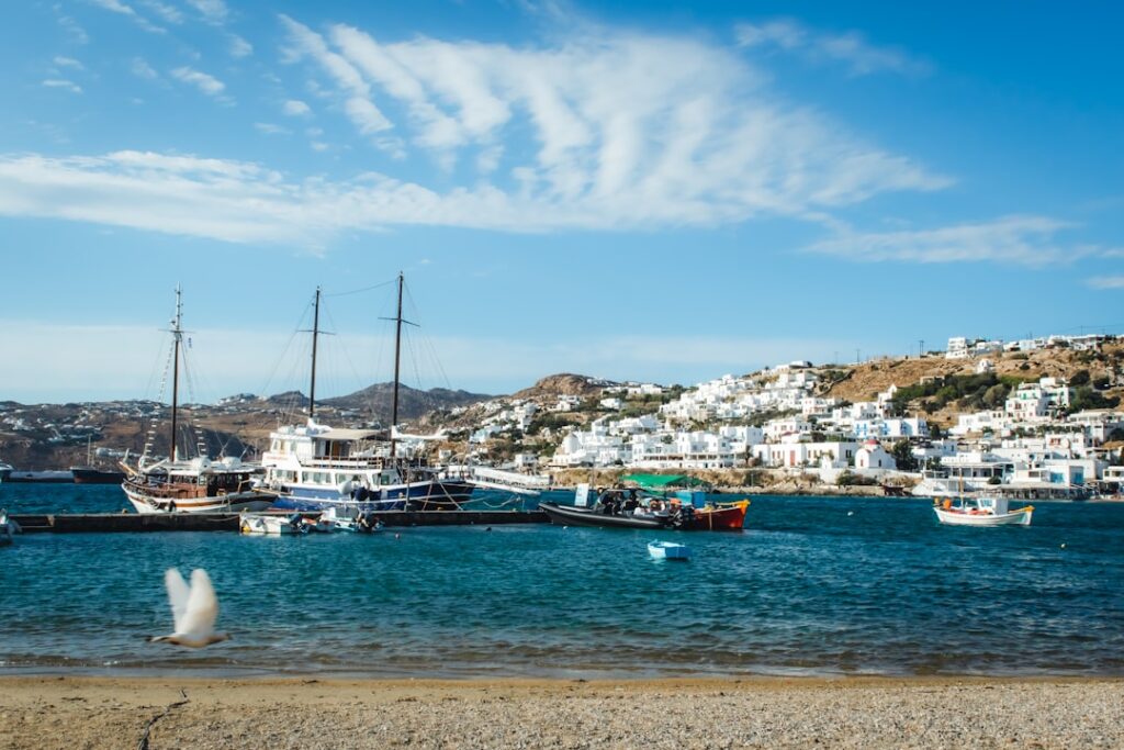 Haven met zeilschepen en witte huizen van Mykonos op de heuvel