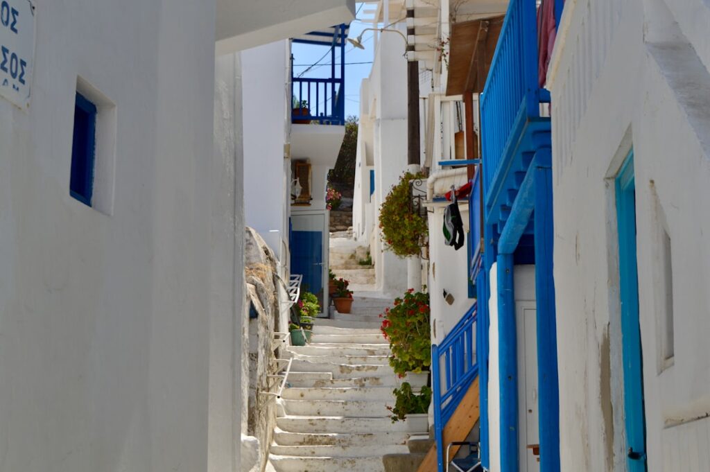 Escalier étroit entre maisons blanches et balcons bleus à Mykonos.