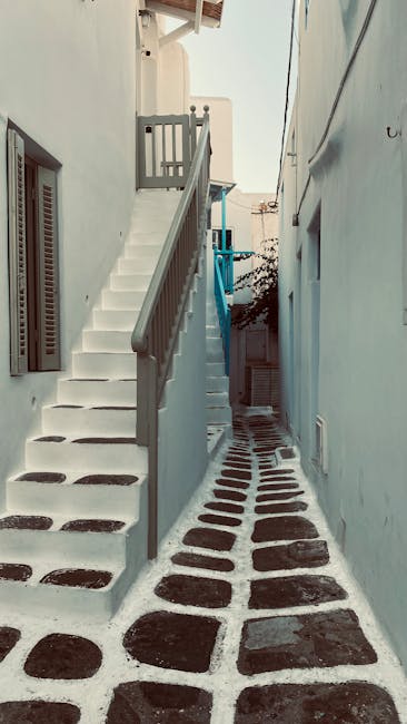 Smal wit steegje met zwart-witte keien en trap in Mykonos