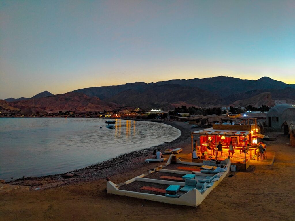Plage tranquille au crépuscule avec bar éclairé et transats près de l'eau à Mykonos.