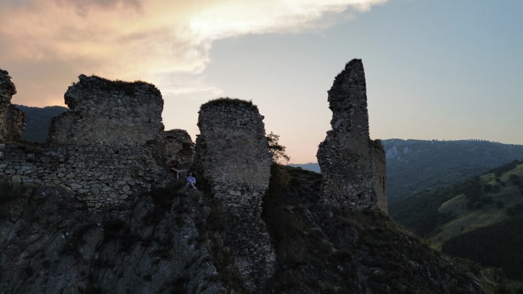 Weathered stone ruins perched on rocky hill at sunset