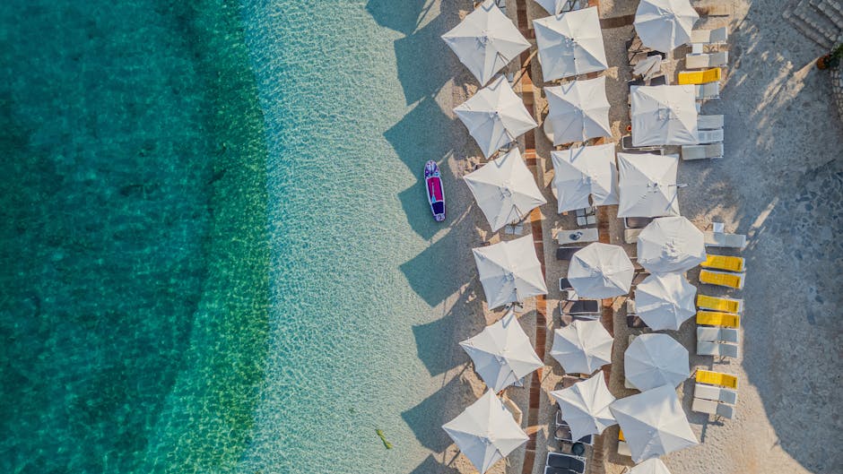 Luchtfoto van rijen witte parasols en fel turquoise water bij Mykonos