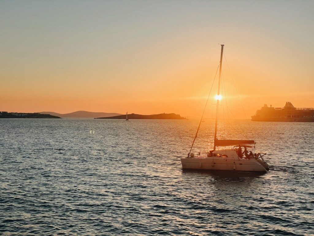 Voilier naviguant au coucher de soleil près des côtes de Mykonos
