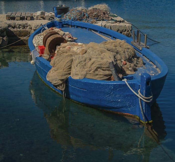 Petite barque de pêche bleue chargée de filets dans le port de Mykonos