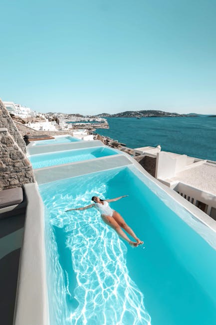 Personne allongée dans une piscine en terrasse surplombant la mer de Mykonos