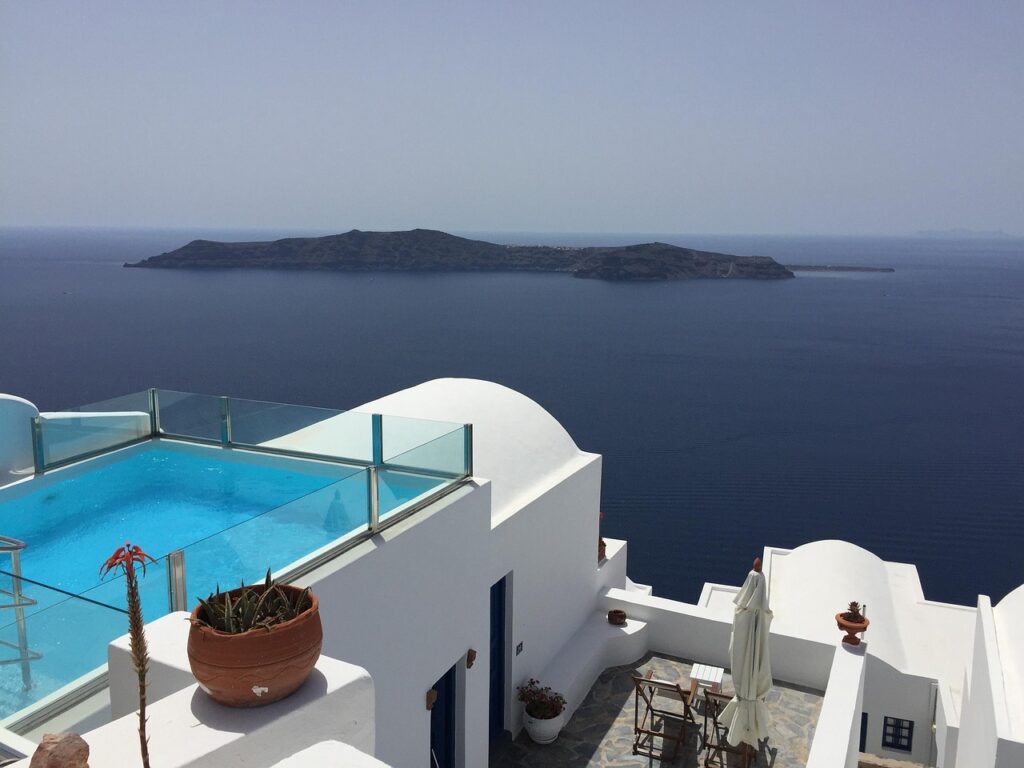 Piscine sur terrasse avec garde-corps en verre et île au loin à Mykonos