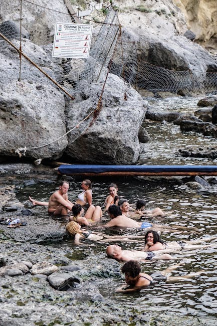 Group of people soaking in rocky coastal hot springs near Mykonos