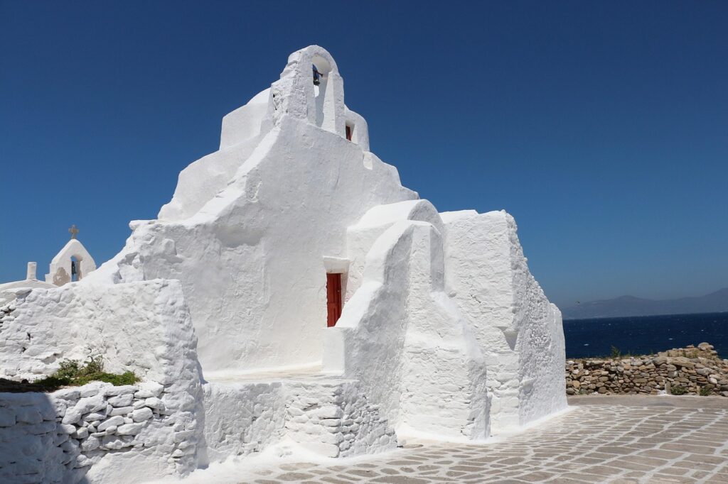 Witte Cycladische kerk bij zee op Mykonos met helderblauwe lucht