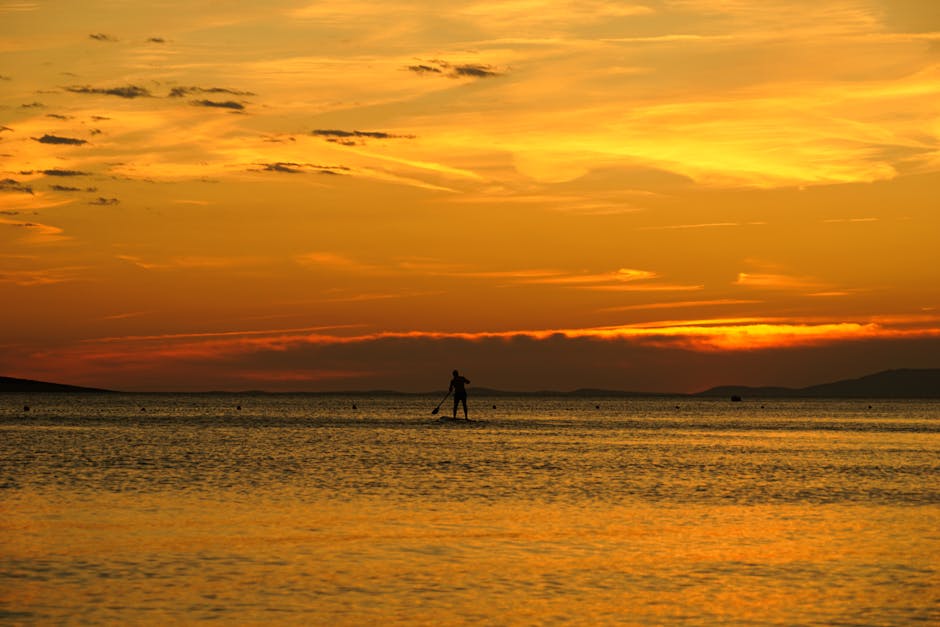 Paddle solitaire silhouetté sur l'eau dorée au coucher du soleil, Mykonos