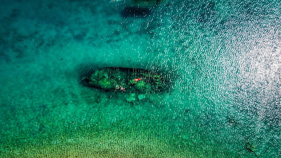 Luchtfoto van een scheepswrak onder turquoise water bij Mykonos met snorkelaars