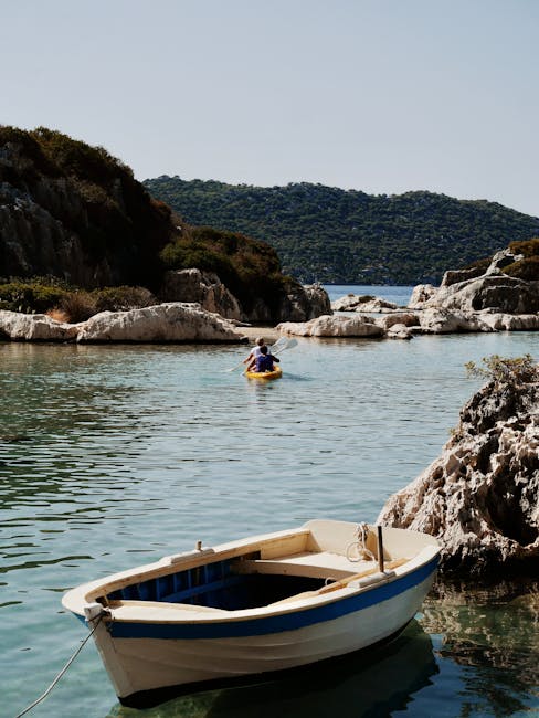 Small moored rowboat and kayakers in a quiet Mykonos inlet