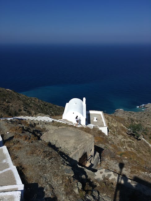 White chapel perched on cliffs overlooking deep blue Mykonos sea