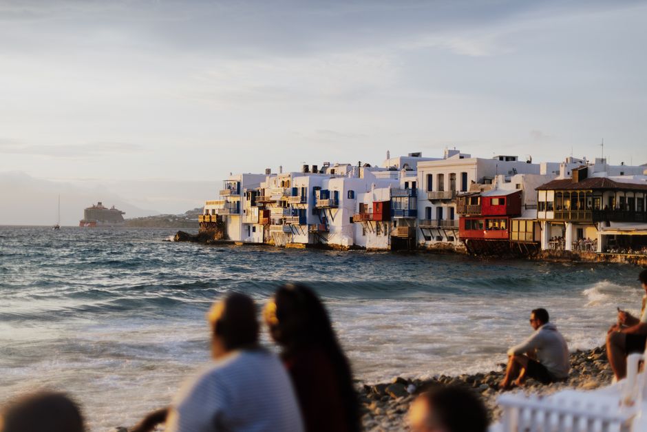 Toeristen op het strand kijken naar de Little Venice-huizen in Mykonos