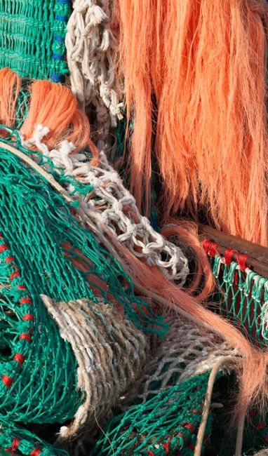 Stapels felgekleurde visnetten in oranje en groen op Mykonos