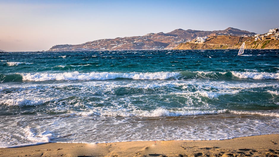 Plage venteuse à Mykonos avec vagues et maisons blanches sur la côte