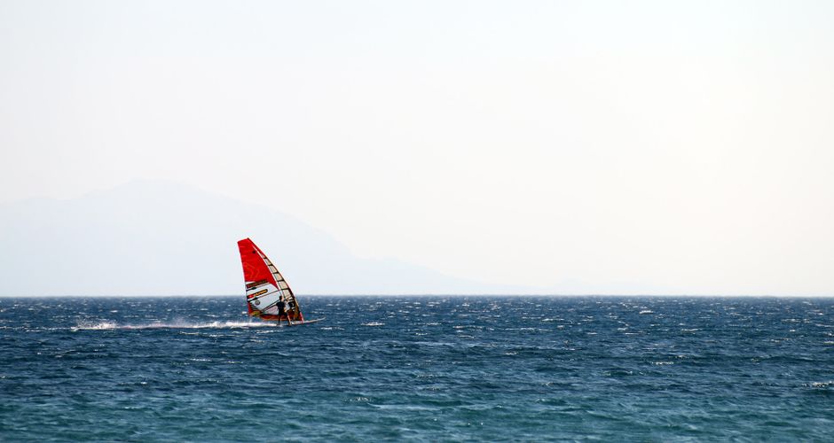 Planche à voile au gréement rouge naviguant sur la mer de Mykonos