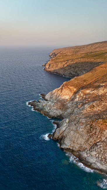 Steep golden sea cliffs curving along Serifos coastline at dusk