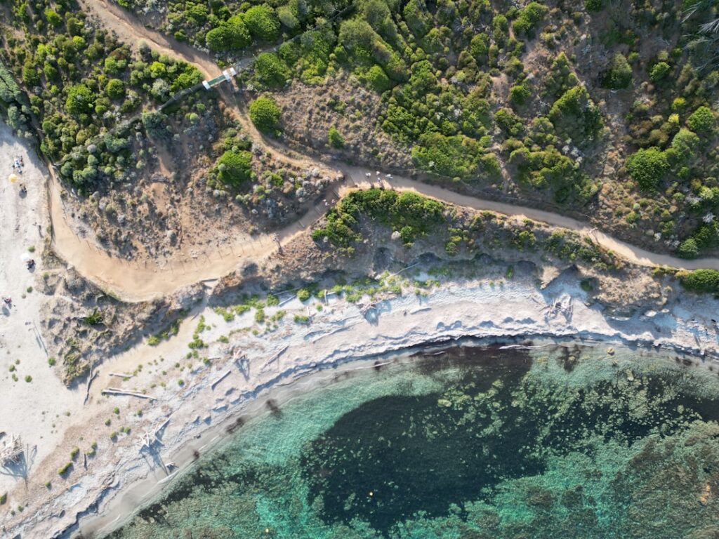 Aerial view of coastal hiking trail, scrub and turquoise water