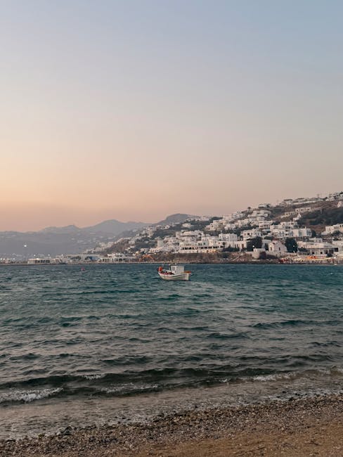 Klein vissersbootje op zee voor witte huizen van Mykonos kust